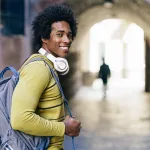 joven-afroamericano-con-swueter-amarillo-y-mochila-camiando-viviendo-en-colivin-en-granada- Estilo de vida coliving en Granada beneficios y actualidad