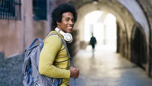 joven-afroamericano-con-swueter-amarillo-y-mochila-camiando-viviendo-en-colivin-en-granada- Estilo de vida coliving en Granada beneficios y actualidad